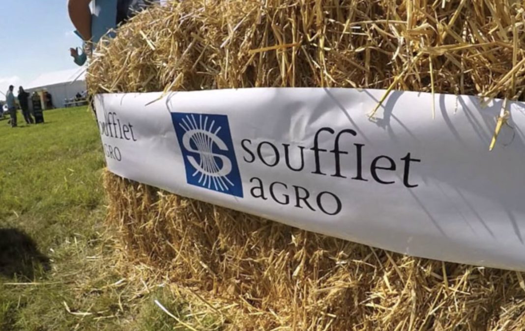 Hay bale wrapped with a banner reading 'Soufflet Agro' and a blue logo, at an outdoor agricultural event.